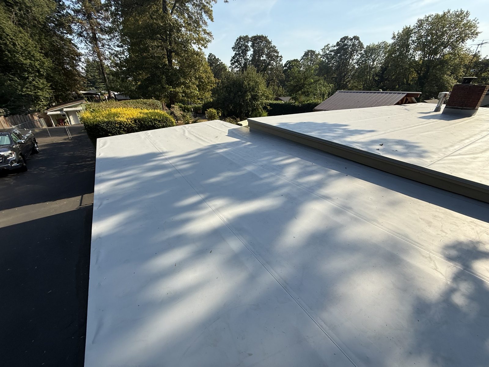Completed TPO flat roof replacement with heat-welded membrane and new chimney flashing